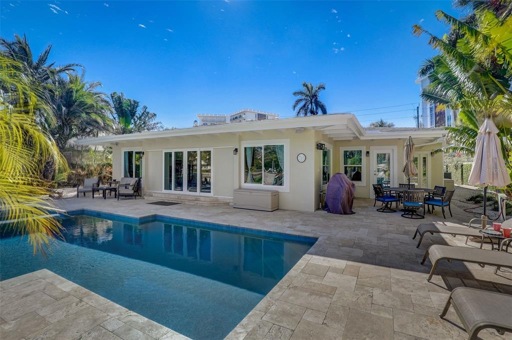 A backyard features a swimming pool, stone patio, outdoor dining area, and a single-story house — 39 S POLK DRIVE, SARASOTA, FL
