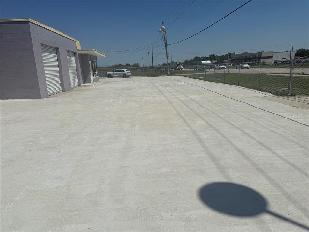 A large, empty concrete parking lot sits in front of a small commercial building — 20600 HWY 27, LAKE WALES, FL