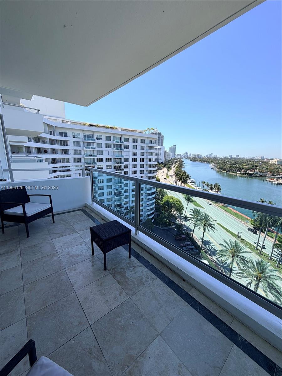 A balcony with tile flooring overlooks a waterway, a road, and nearby high-rise buildings — 5161 Collins Ave # 1506, Miami Beach FL 33140, MIAMI BEACH, FL