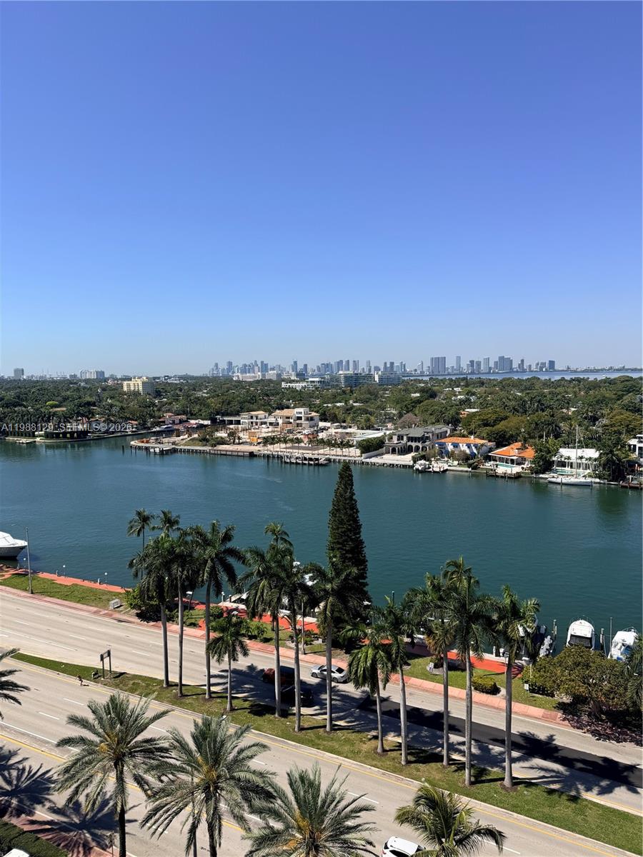 An elevated view of a waterway, palm trees, and a distant city skyline — 5161 Collins Ave # 1506, Miami Beach FL 33140, MIAMI BEACH, FL
