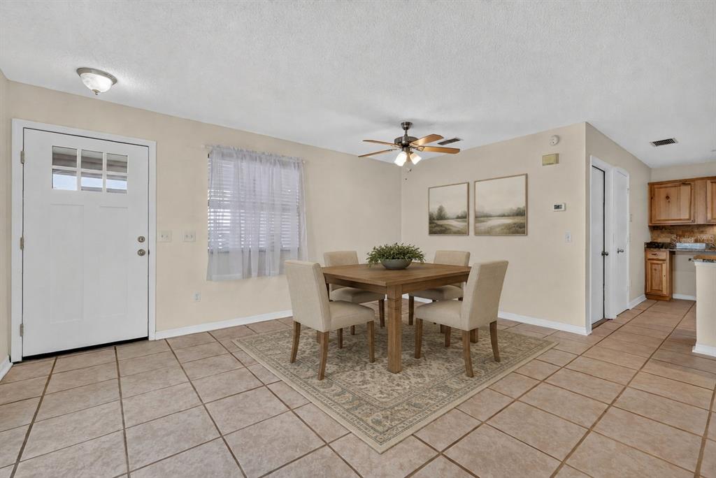 A dining area with a square wooden table, four chairs, and tile flooring — 483 HILDALGO DRIVE, THE VILLAGES, FL