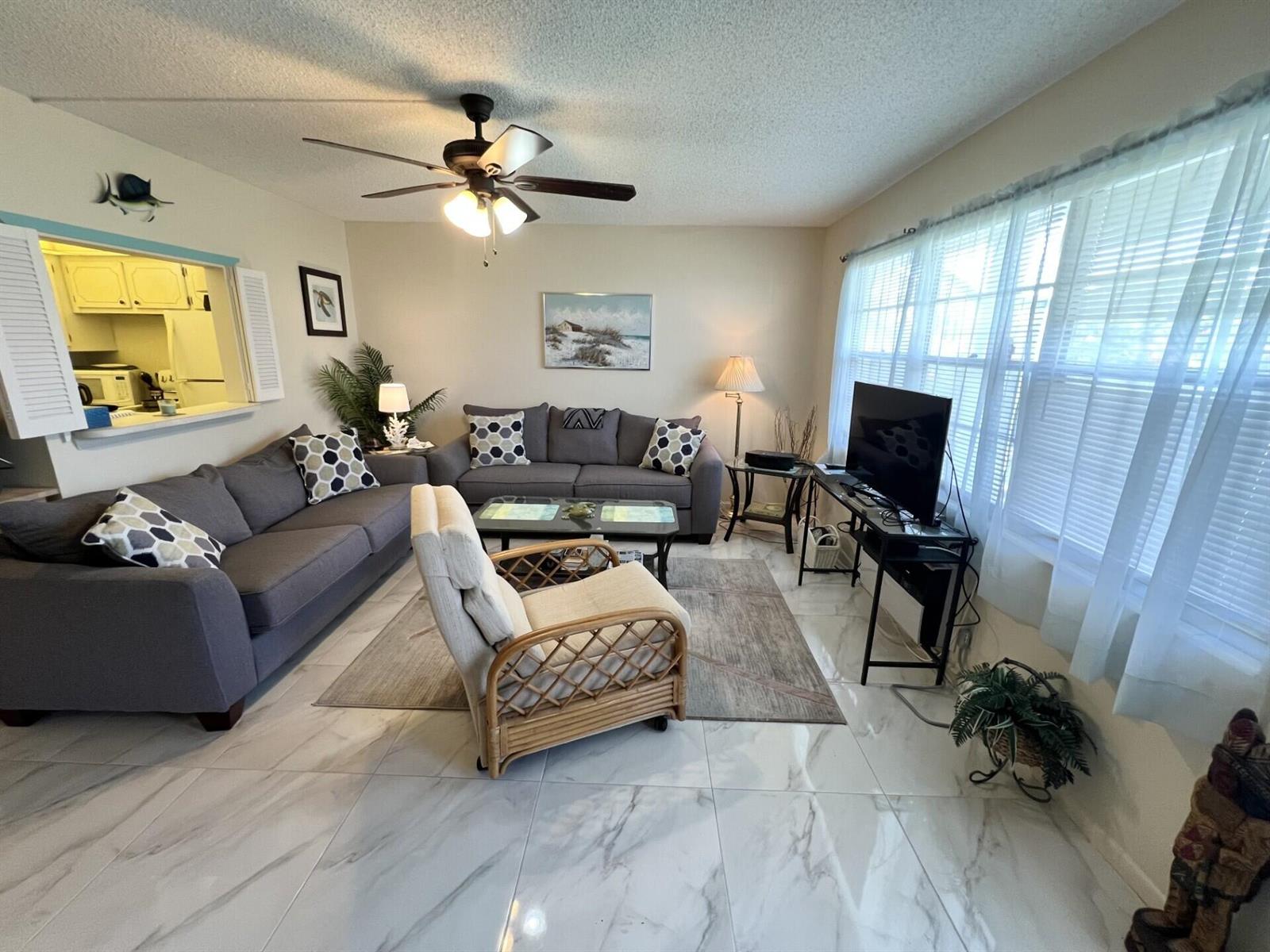 A living room with gray sofas, a rattan chair, tile flooring, and a ceiling fan — 3 Islewood A # 3, Deerfield Beach FL 33442, DEERFIELD BEACH, FL
