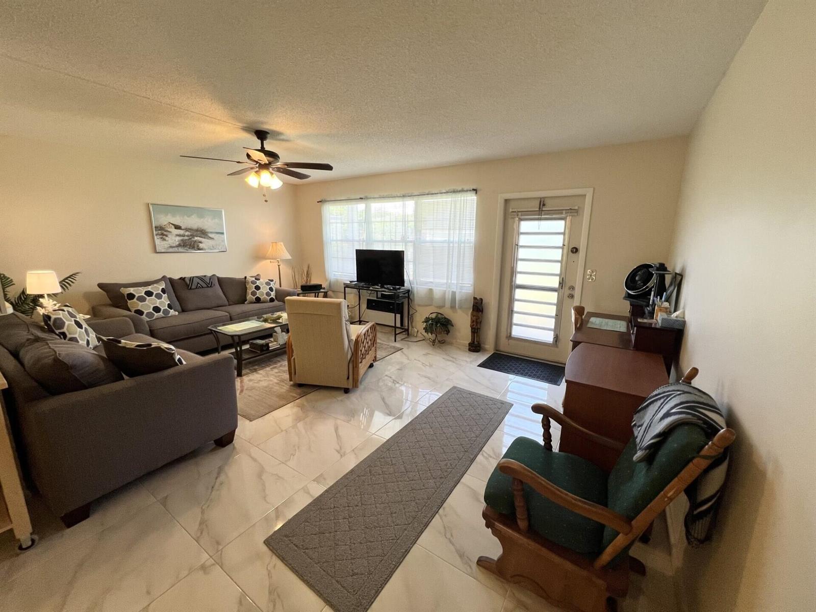 A living room features gray sofas, a beige armchair, a rocking chair, and marble-look tile flooring — 3 Islewood A # 3, Deerfield Beach FL 33442, DEERFIELD BEACH, FL