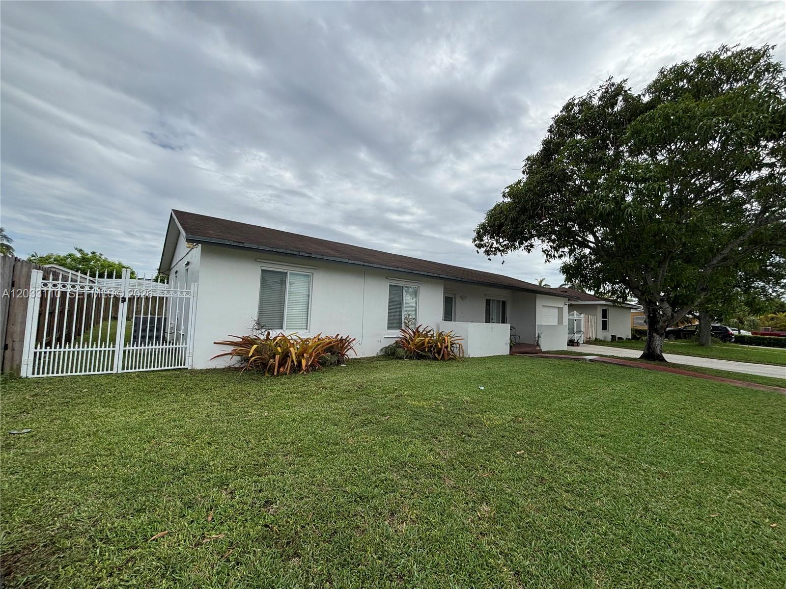 A single-story white house with a brown roof, a gated driveway, and a large tree — 11104 SW 155th Ter, Miami FL 33157, MIAMI, FL