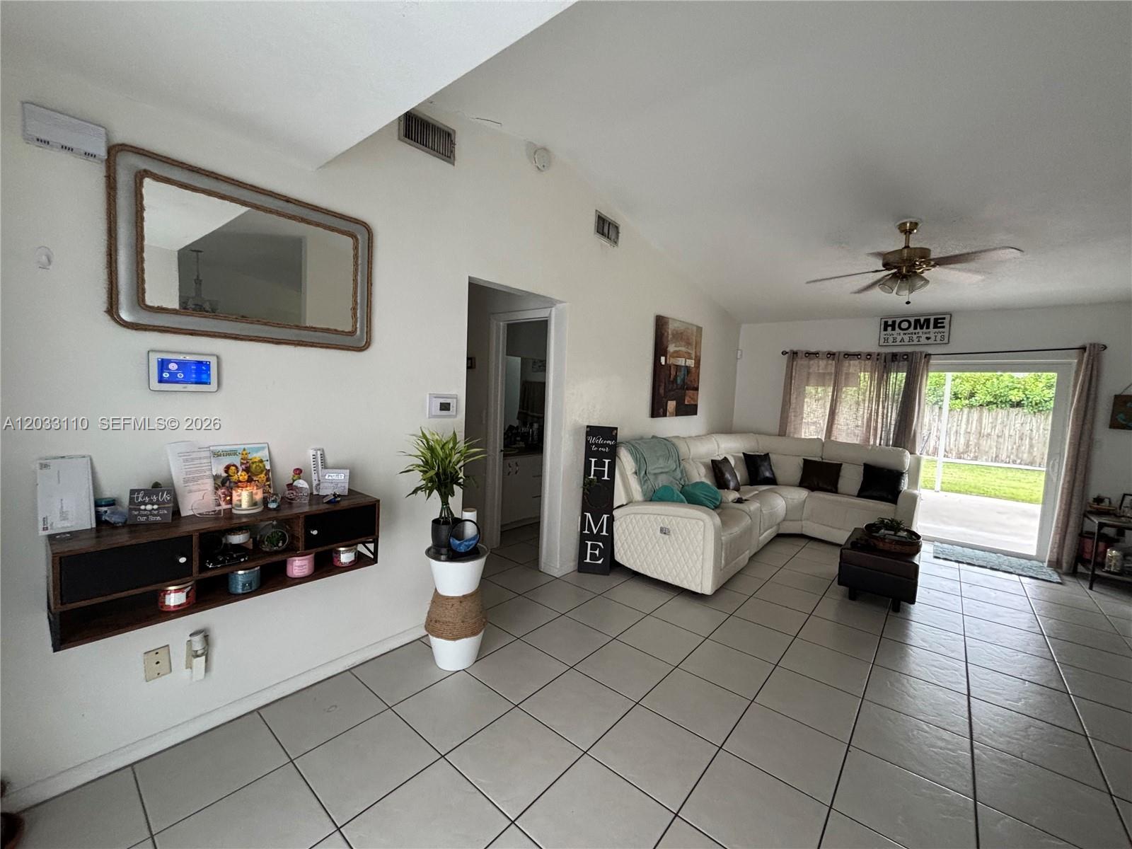 A living room features white tile floors, a white sectional sofa, and a wall-mounted shelf — 11104 SW 155th Ter, Miami FL 33157, MIAMI, FL