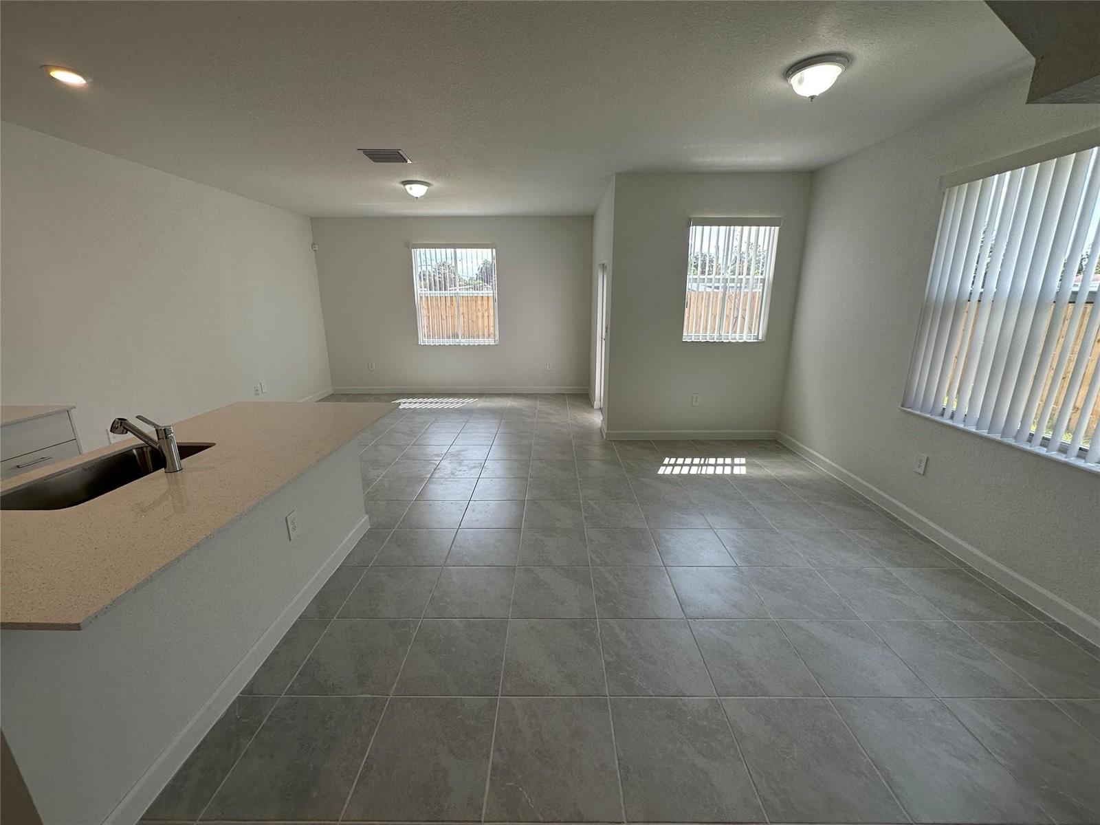 An open-concept kitchen and living area features light gray tile flooring and white walls — 2437 NW 131st Circle, Miami FL 33167, MIAMI, FL