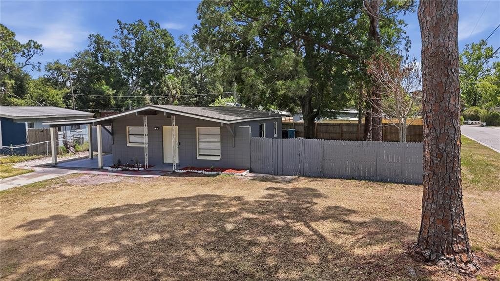 A gray single-story house with a carport and a wooden fence sits on a lot — 1401 RADLEIGH PLACE, ORLANDO, FL