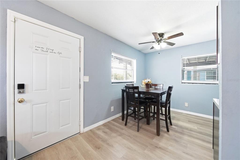 A dining area with light blue walls, wood-look flooring, a table for four, and a door — 1401 RADLEIGH PLACE, ORLANDO, FL