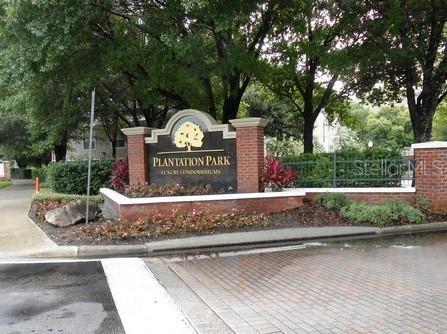 A brick monument sign for Plantation Park Luxury Condominiums stands near a tree-lined entrance — 13013 MULBERRY PARK DRIVE UNIT 224, ORLANDO, FL