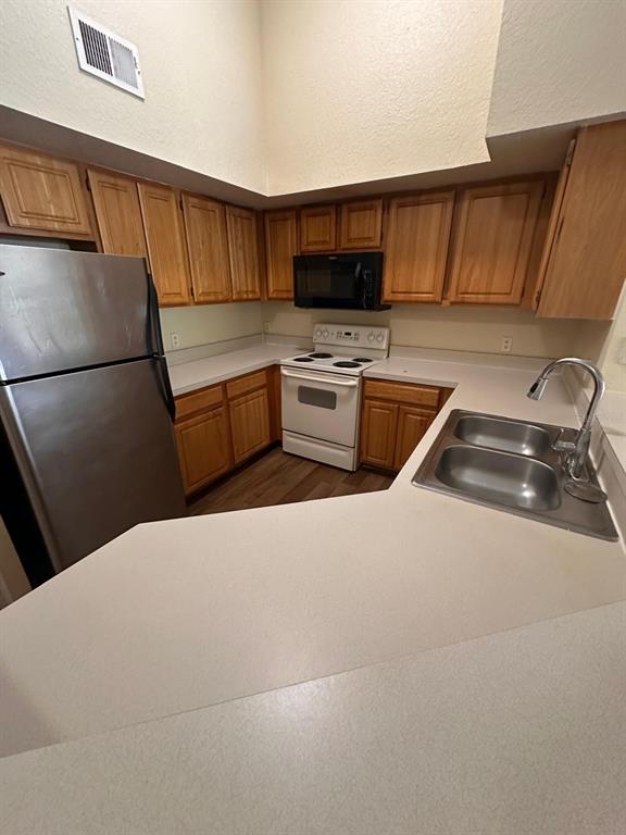 A kitchen features light wood cabinets, white appliances, a stainless steel refrigerator, and laminate countertops — 13013 MULBERRY PARK DRIVE UNIT 224, ORLANDO, FL