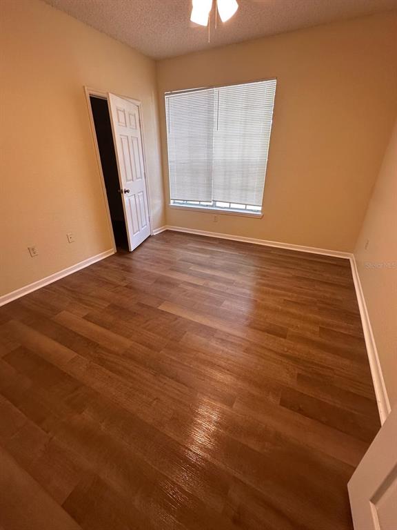 An empty bedroom features light-colored walls, a window with blinds, and wood-look flooring — 13013 MULBERRY PARK DRIVE UNIT 224, ORLANDO, FL