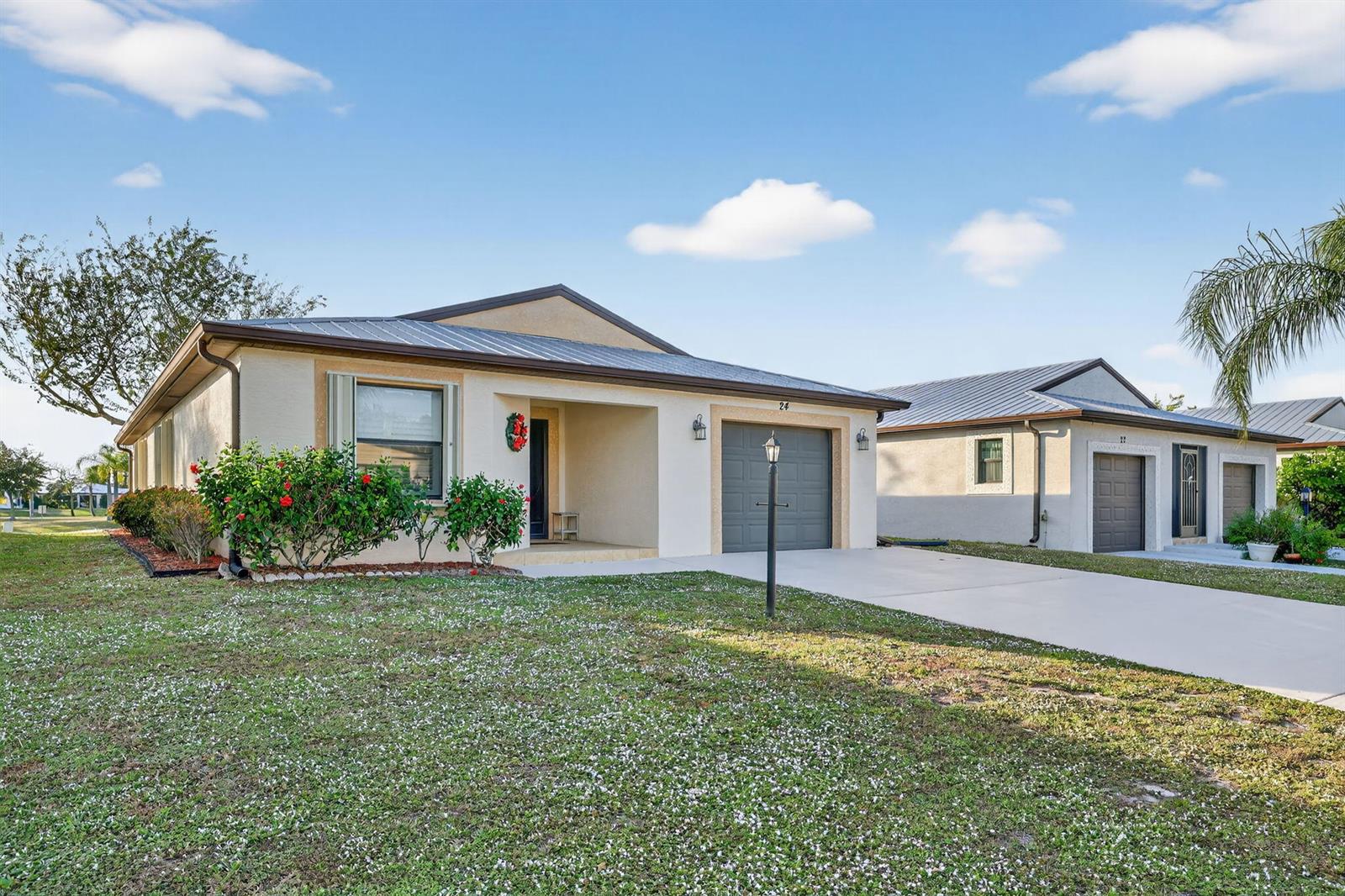 A single-story house with a metal roof, gray garage door, and a front lawn — 24 Azul, Fort Pierce FL 34951, FORT PIERCE, FL