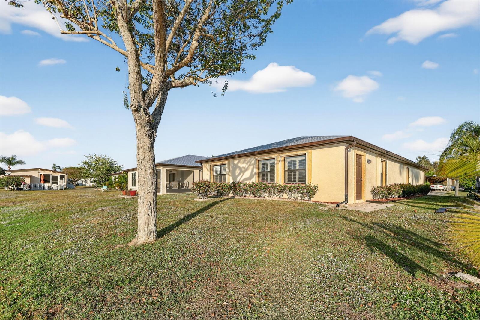 A single-story tan house with a metal roof sits on a grassy lot — 24 Azul, Fort Pierce FL 34951, FORT PIERCE, FL