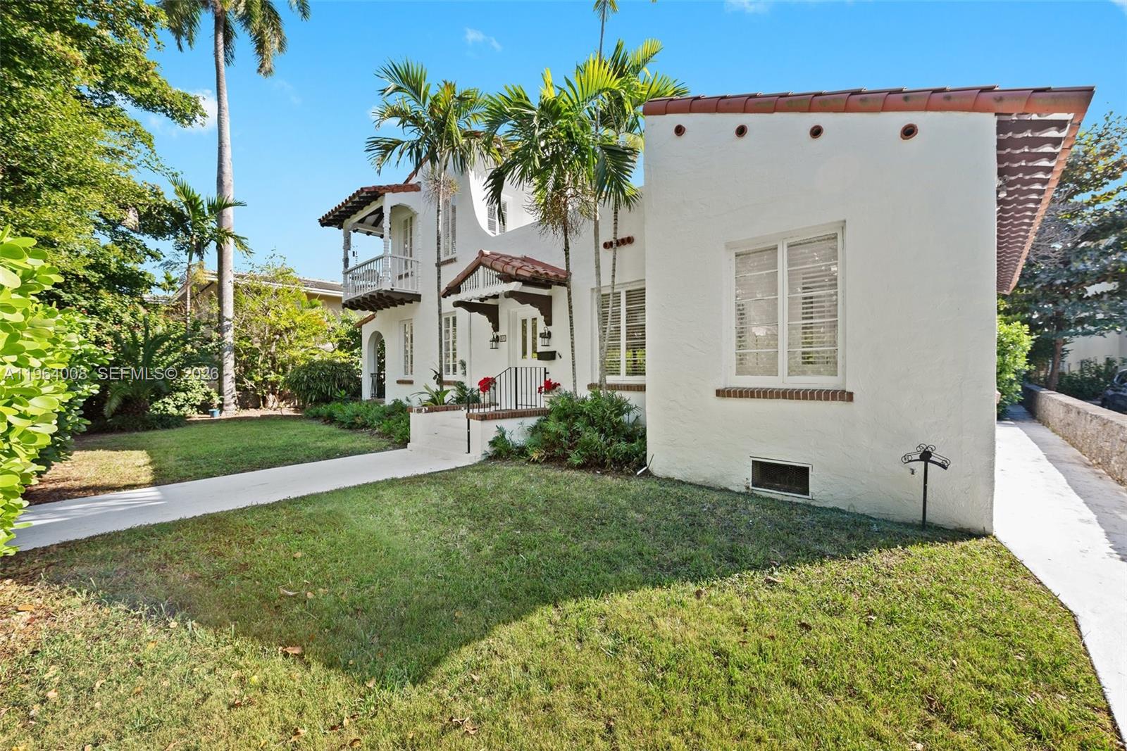 A white two-story Mediterranean-style house features a tiled roof, palm trees, and a front lawn — 36 Phoenetia Ave, Coral Gables FL 33134, CORAL GABLES, FL