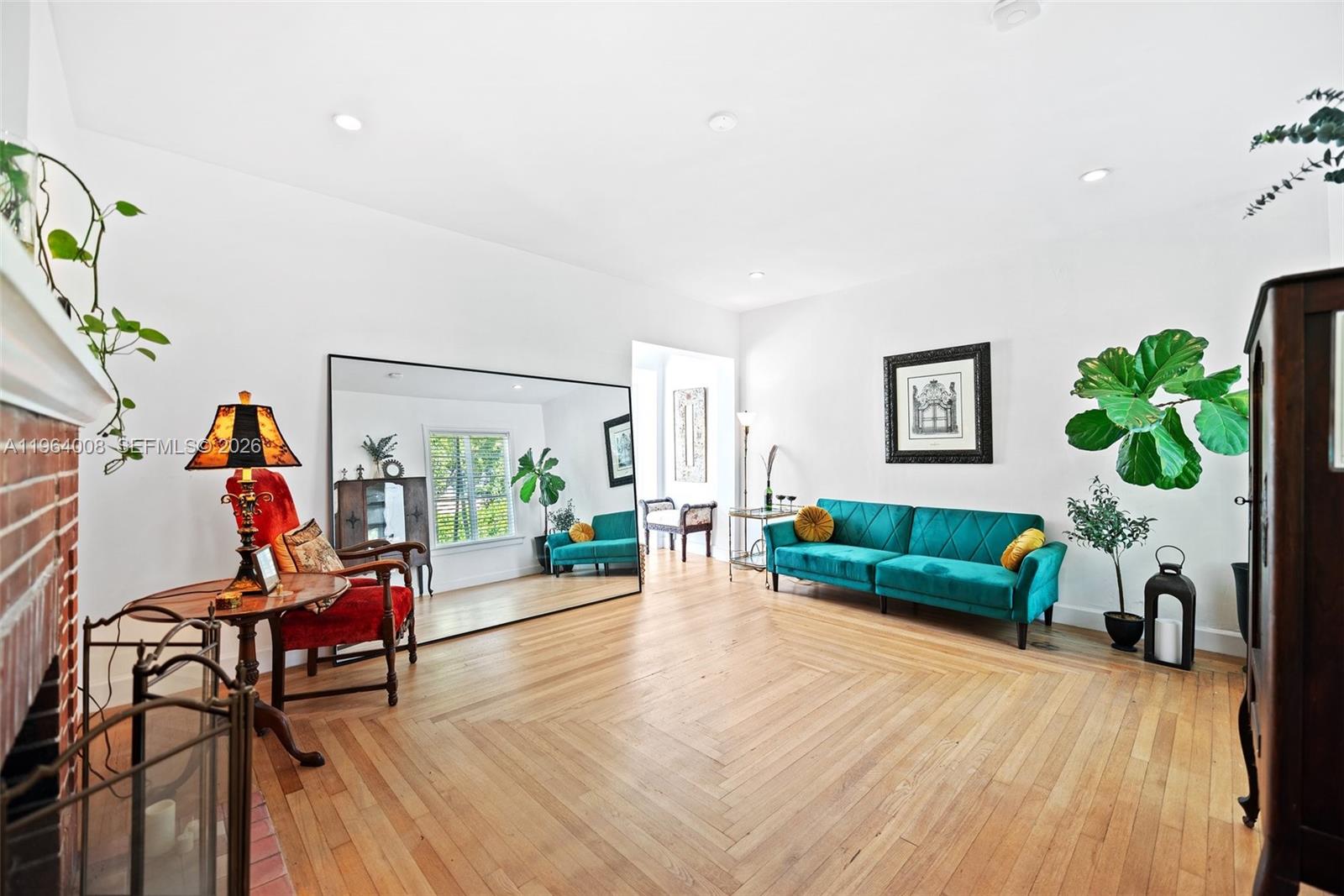 A living room features hardwood floors, a large floor mirror, and a teal velvet sofa — 36 Phoenetia Ave, Coral Gables FL 33134, CORAL GABLES, FL