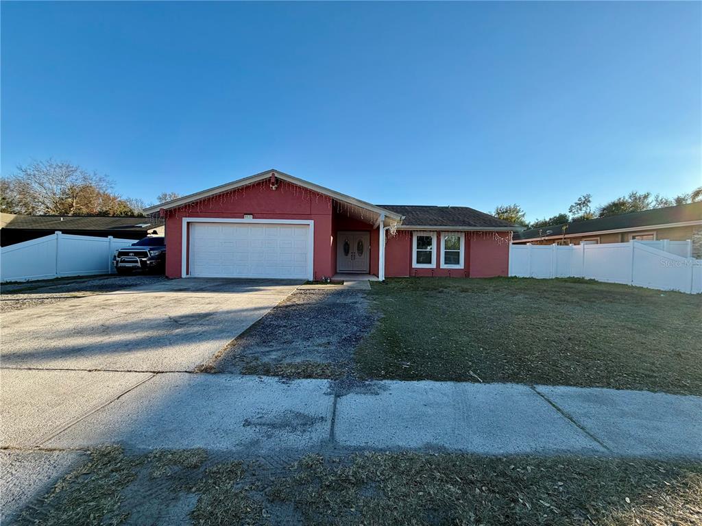 A single-story house with a red exterior, a two-car garage, and a white fence — 8026 JACKSON SPRINGS ROAD, TAMPA, FL