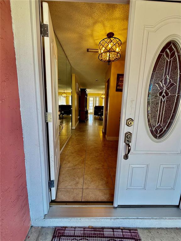 An open white front door reveals a tiled entryway with a hanging light fixture — 8026 JACKSON SPRINGS ROAD, TAMPA, FL