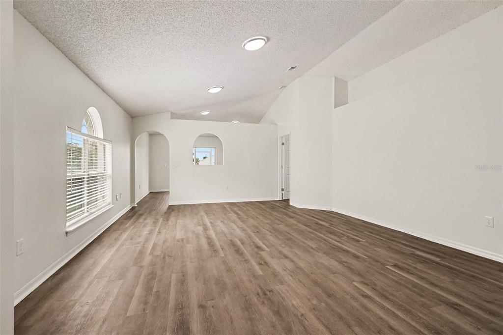 An empty room with white walls, vaulted ceilings, and wood-look flooring — 2056 REDWOOD CIRCLE NE, PALM BAY, FL