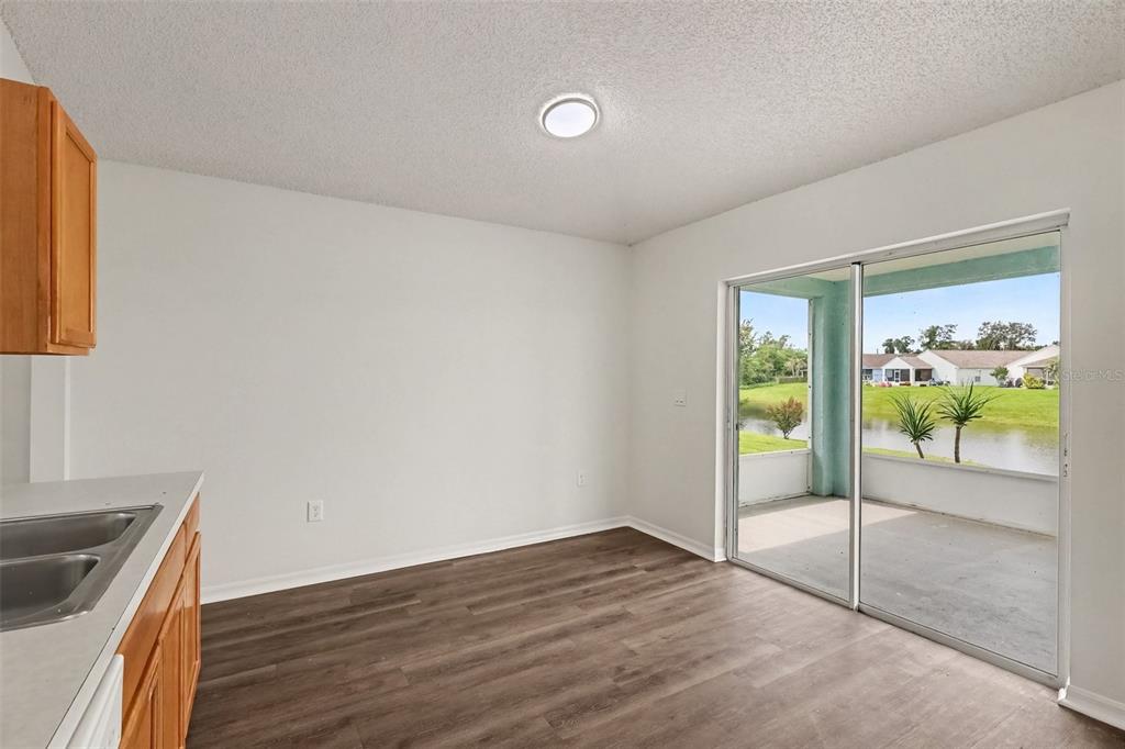 A dining area with wood-look flooring, white walls, and a sliding glass door to a patio — 2056 REDWOOD CIRCLE NE, PALM BAY, FL