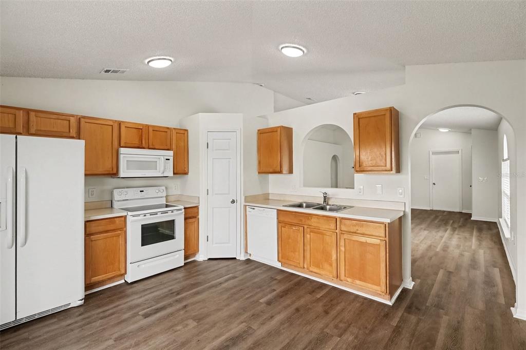 A kitchen with wood cabinets, white appliances, and wood-look flooring — 2056 REDWOOD CIRCLE NE, PALM BAY, FL