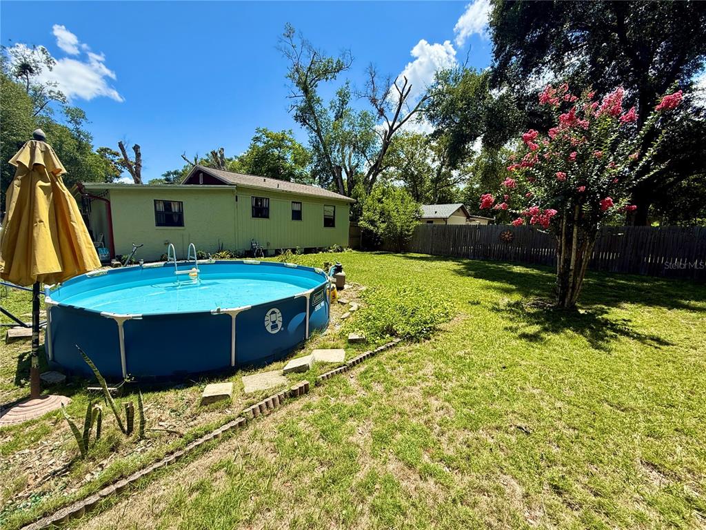 A backyard features a round above-ground pool, a yellow house, and a flowering tree — 5937 UONA AVENUE, ORLANDO, FL