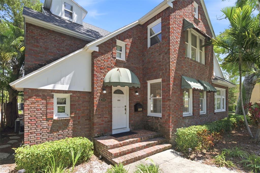 A two-story brick house with a white front door and green fabric awnings — 555 18TH AVENUE NE, ST PETERSBURG, FL