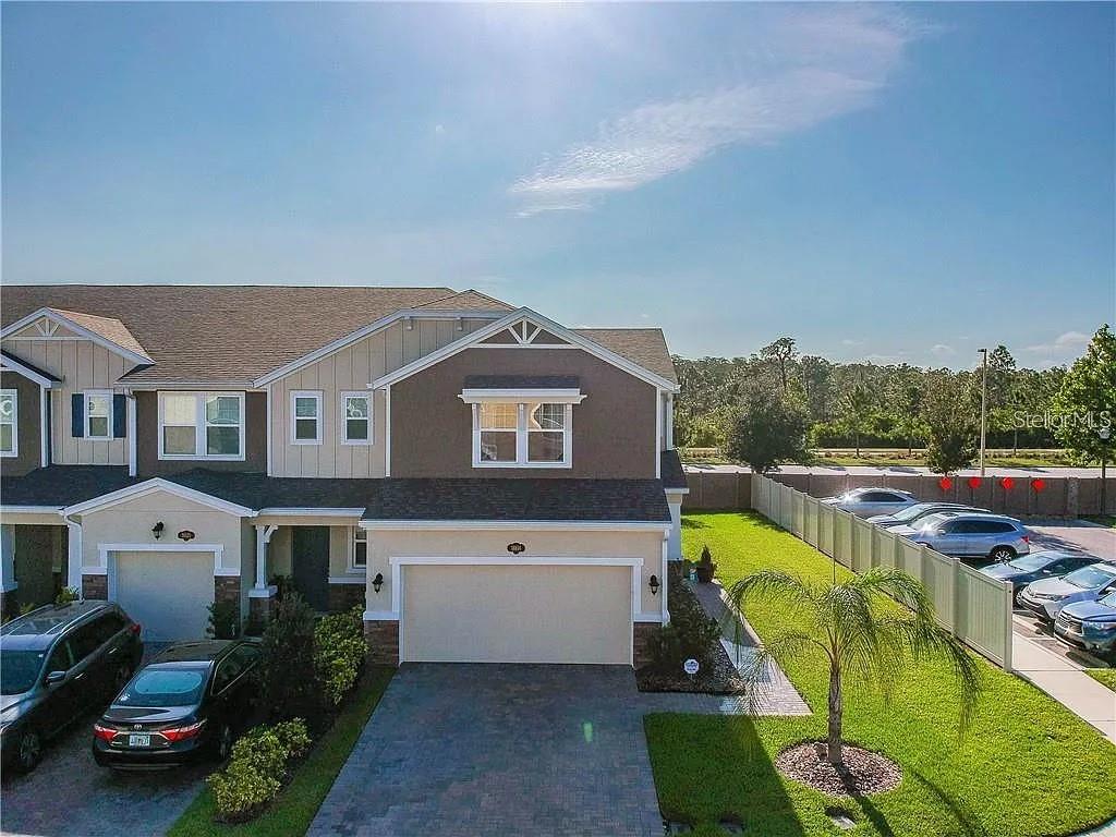 An exterior view of a two-story townhouse with a two-car garage and a side yard — 18814 CORNUTA STREET, LUTZ, FL