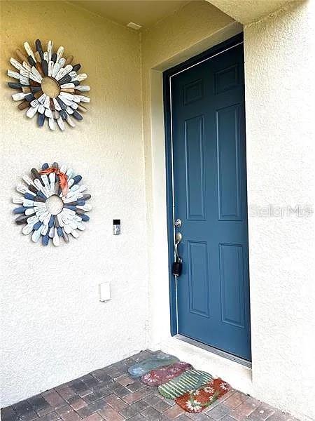 A blue front door with two decorative wreaths on the adjacent exterior wall — 18814 CORNUTA STREET, LUTZ, FL