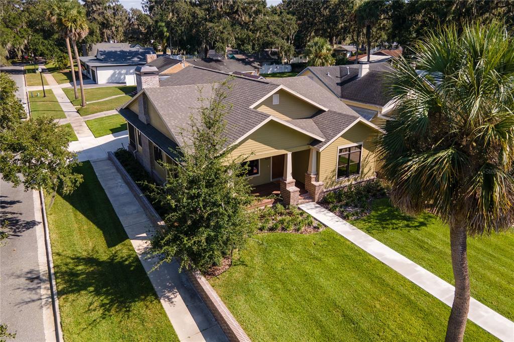 An aerial view of a single-story house with tan siding, a shingled roof, and landscaping — 1000 S 9TH STREET, LEESBURG, FL