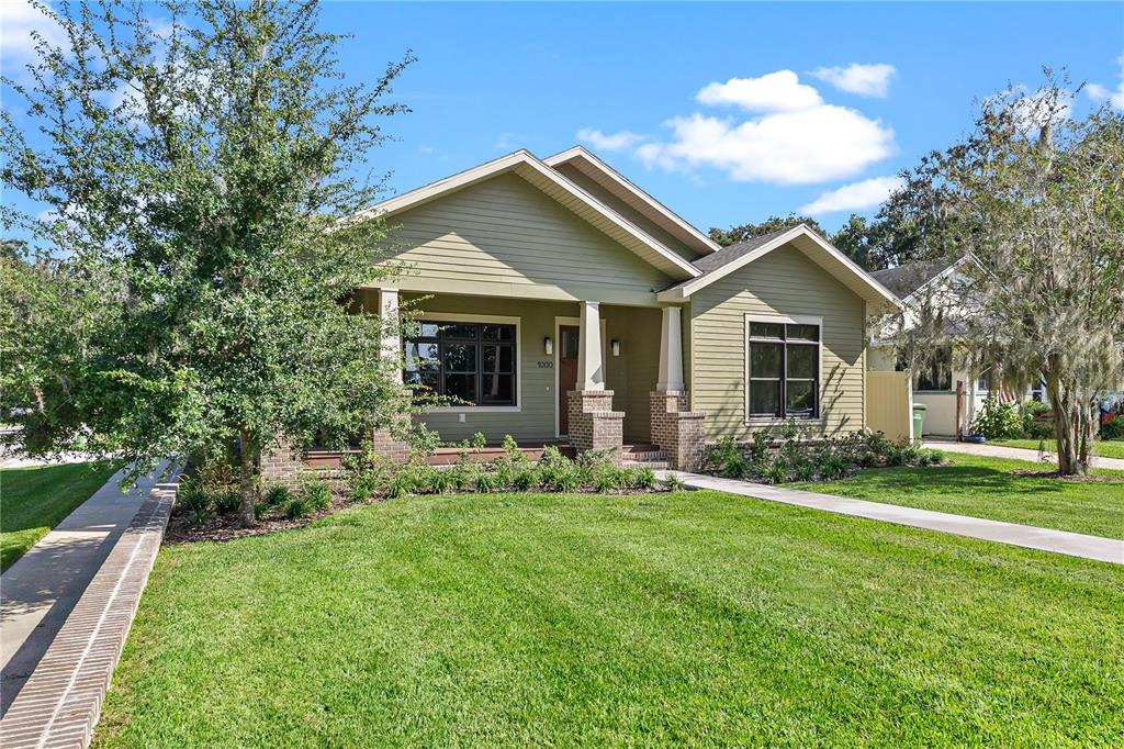 A single-story house with olive green siding, a front porch, and a brick-trimmed walkway — 1000 S 9TH STREET, LEESBURG, FL