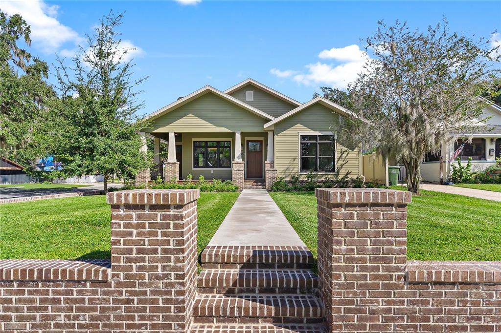 A green single-story house with a brick wall and walkway in the front yard — 1000 S 9TH STREET, LEESBURG, FL