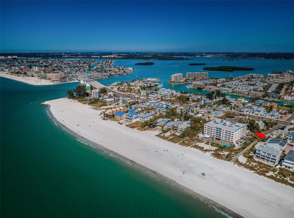 An aerial view shows a white sand beach, coastal homes, and a large resort building — 12274 1ST STREET W UNIT 8, TREASURE ISLAND, FL