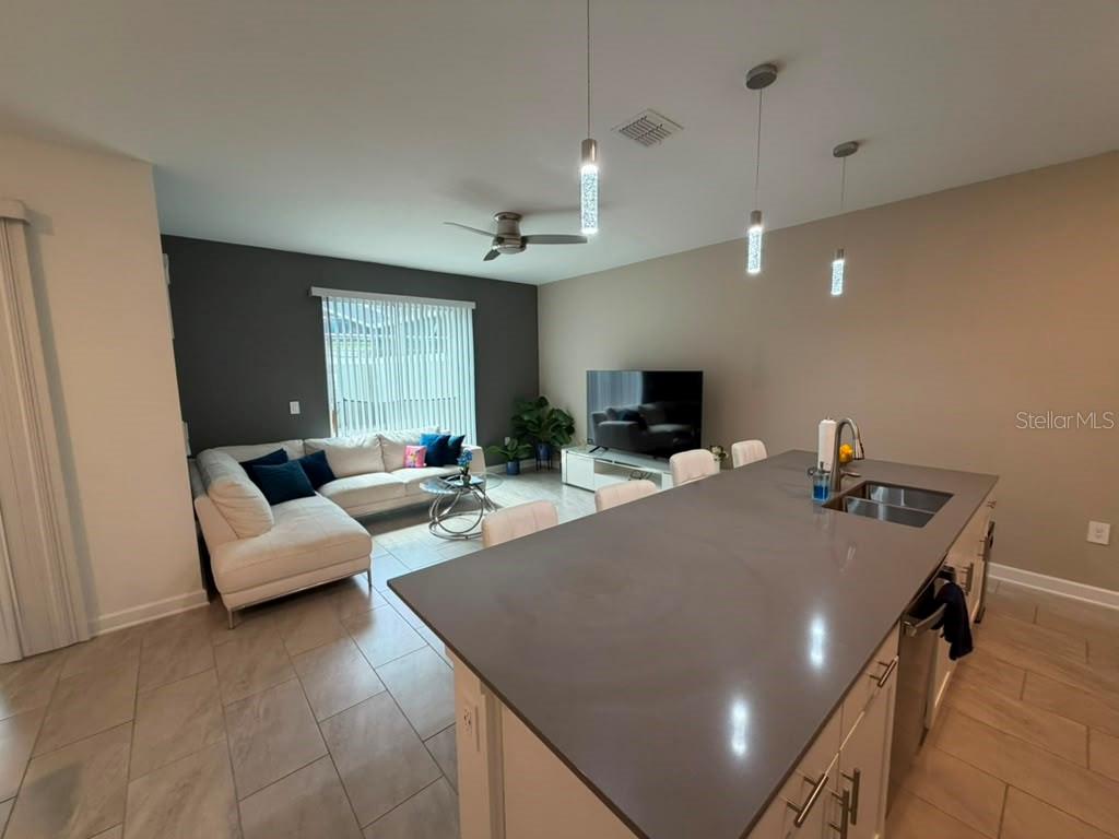 An open-concept kitchen with a large island overlooks a living room with a sectional sofa — 1172 KINGSBARN STREET, DAVENPORT, FL