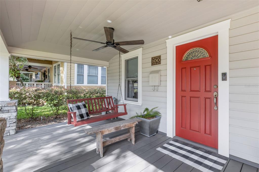 A covered front porch features a red door, a hanging bench, and a wooden bench — 717 JOHNSON AVENUE, LAKELAND, FL
