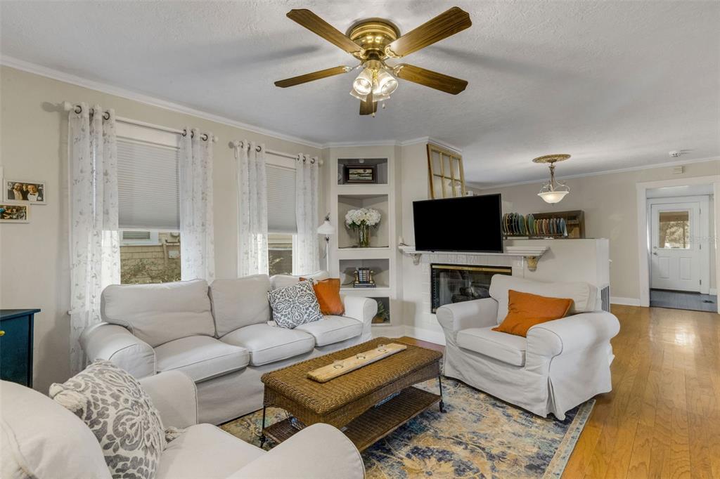 A living room features a white sofa, armchair, fireplace, built-in shelving, and hardwood floors — 717 JOHNSON AVENUE, LAKELAND, FL