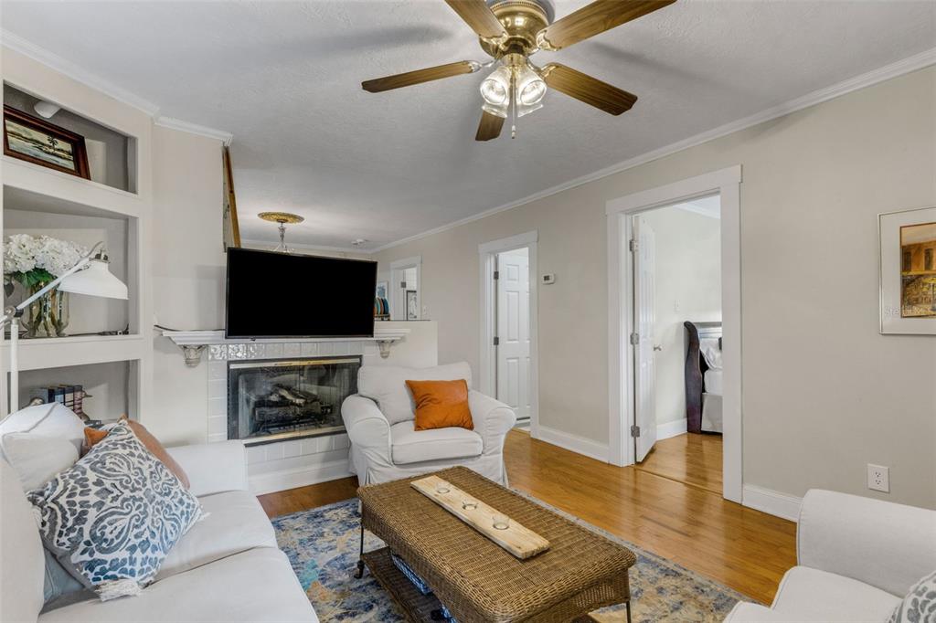A living room features a fireplace, a mounted television, white furniture, and hardwood floors — 717 JOHNSON AVENUE, LAKELAND, FL