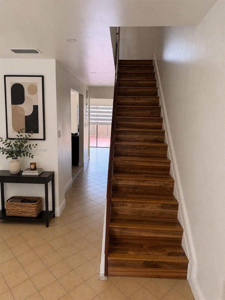 A wooden staircase leads upward next to a hallway with tile flooring and a console table — 13335 SW 57th Ter # 3, Miami FL 33183, MIAMI, FL