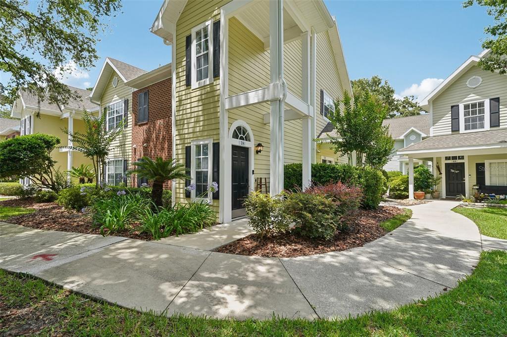 A two-story yellow townhouse with a black front door and a concrete walkway — 10000 SW 52ND AVENUE UNIT G38, GAINESVILLE, FL