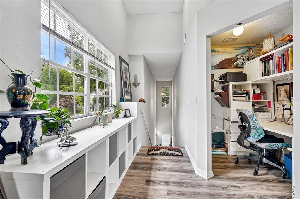 A living room features light wood-look flooring, a ceiling fan, and an adjacent kitchen area — 10000 SW 52ND AVENUE UNIT G38, GAINESVILLE, FL