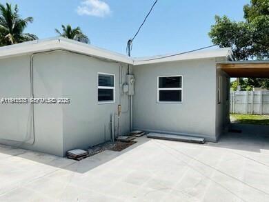 The exterior of a light gray house features a concrete patio and a covered carport — 804 N 20th Ct, Hollywood FL 33020, HOLLYWOOD, FL