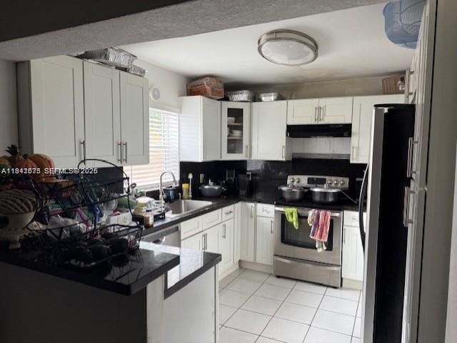 A kitchen features white cabinets, black countertops, stainless steel appliances, and white tile flooring — 804 N 20th Ct, Hollywood FL 33020, HOLLYWOOD, FL