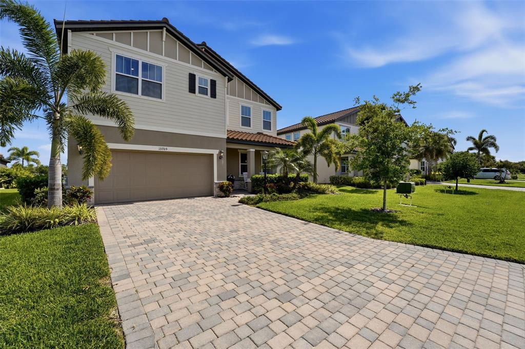 A two-story suburban house with a paved driveway, a two-car garage, and palm trees — 13705 FLAT WOODS TERRACE, BRADENTON, FL