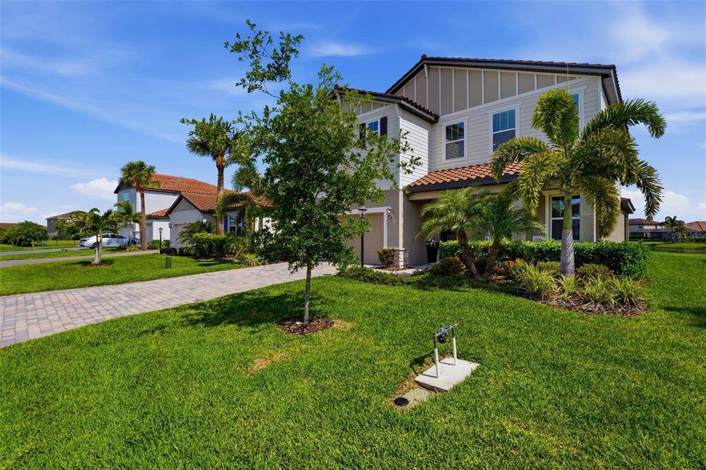 A two-story suburban house with a paved driveway, green lawn, and palm trees — 13705 FLAT WOODS TERRACE, BRADENTON, FL