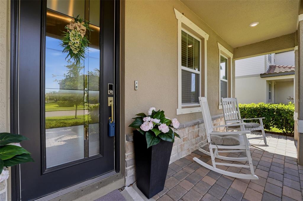 A covered front porch features a dark door, two white rocking chairs, and a planter — 13705 FLAT WOODS TERRACE, BRADENTON, FL