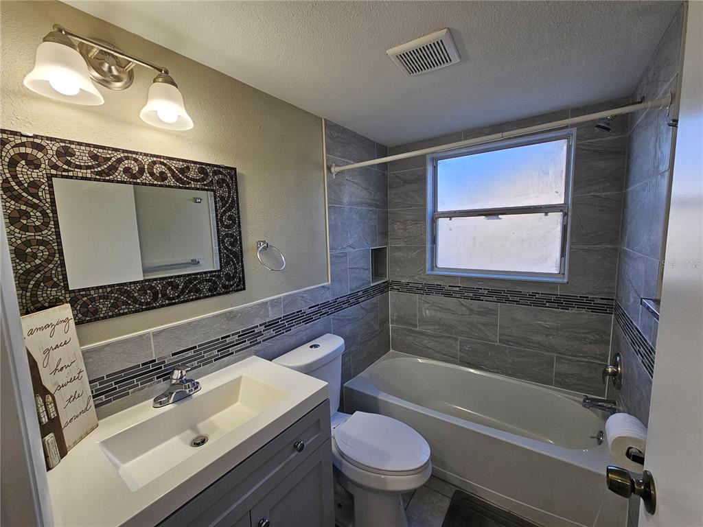 A bathroom features a gray vanity, a toilet, and a tiled bathtub shower combination — 8200 FAIRWAYS CIRCLE UNIT B102, OCALA, FL