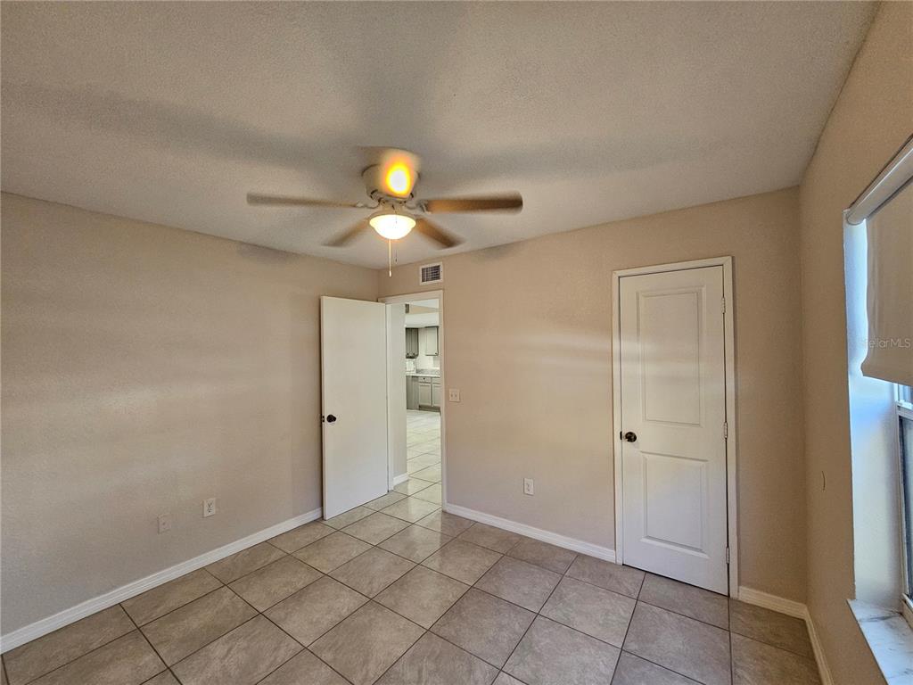 A room with tan walls, a ceiling fan, tiled floors, and two white doors — 8200 FAIRWAYS CIRCLE UNIT B102, OCALA, FL