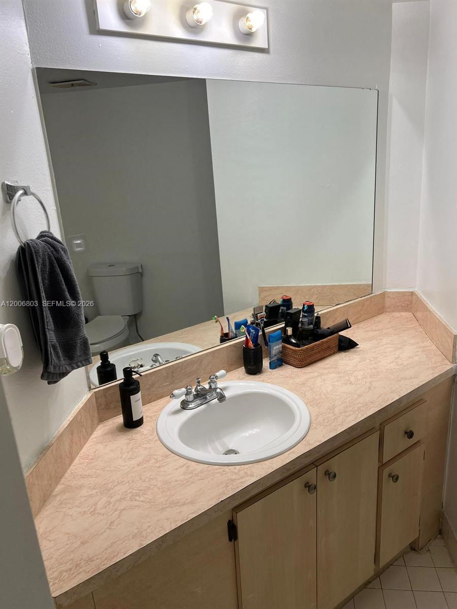 A bathroom features a vanity with a light-colored countertop, a sink, and a large mirror — 7125 NW 186th St # B502, Hialeah FL 33015, HIALEAH, FL