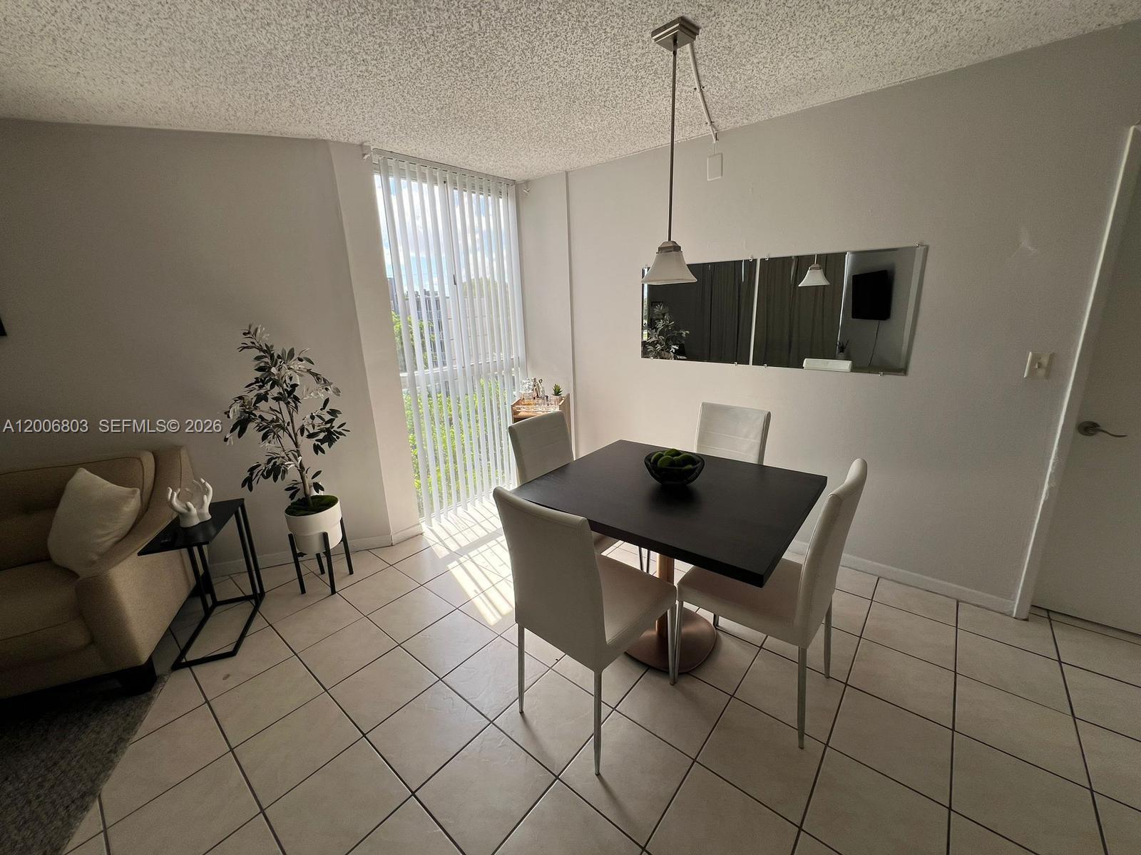 A dining area features a square table, four chairs, tile flooring, and a sliding glass door — 7125 NW 186th St # B502, Hialeah FL 33015, HIALEAH, FL