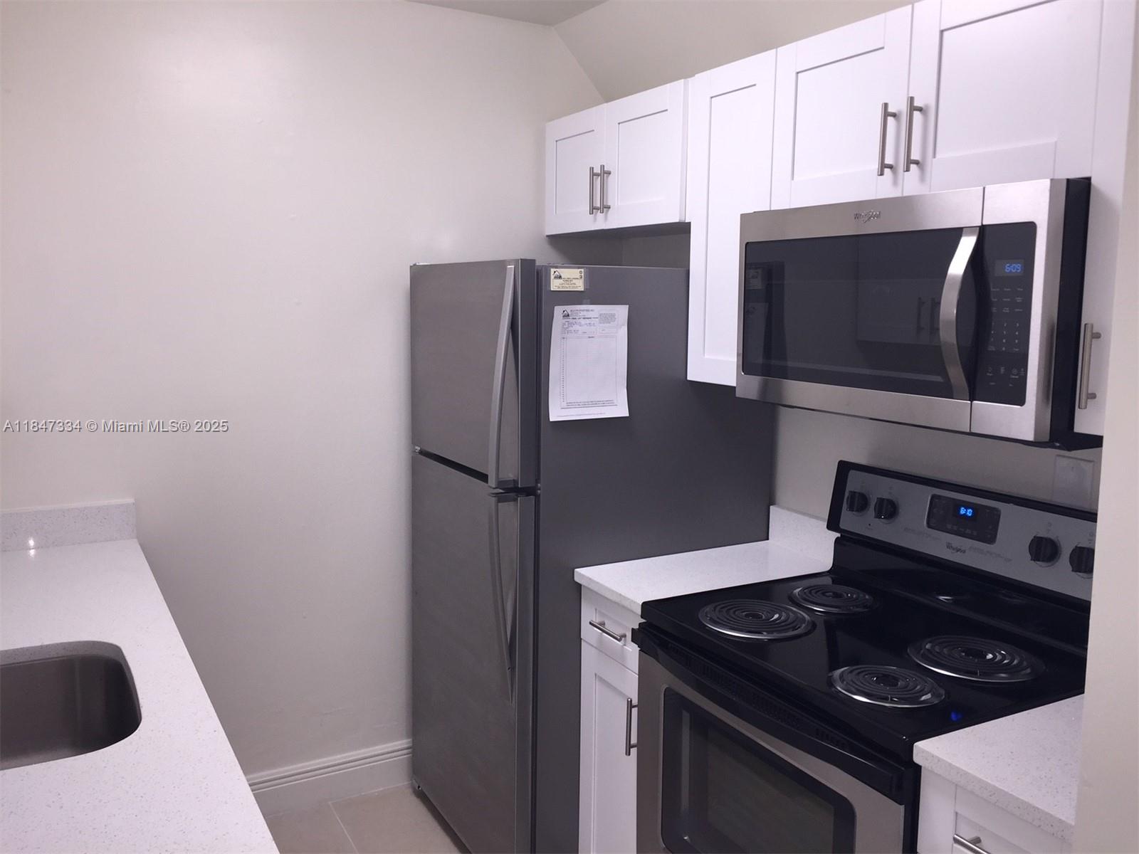 A kitchen features white cabinets, stainless steel appliances, and light-colored countertops — 10740 N KENDALL DR # 14, Miami FL 33176, MIAMI, FL