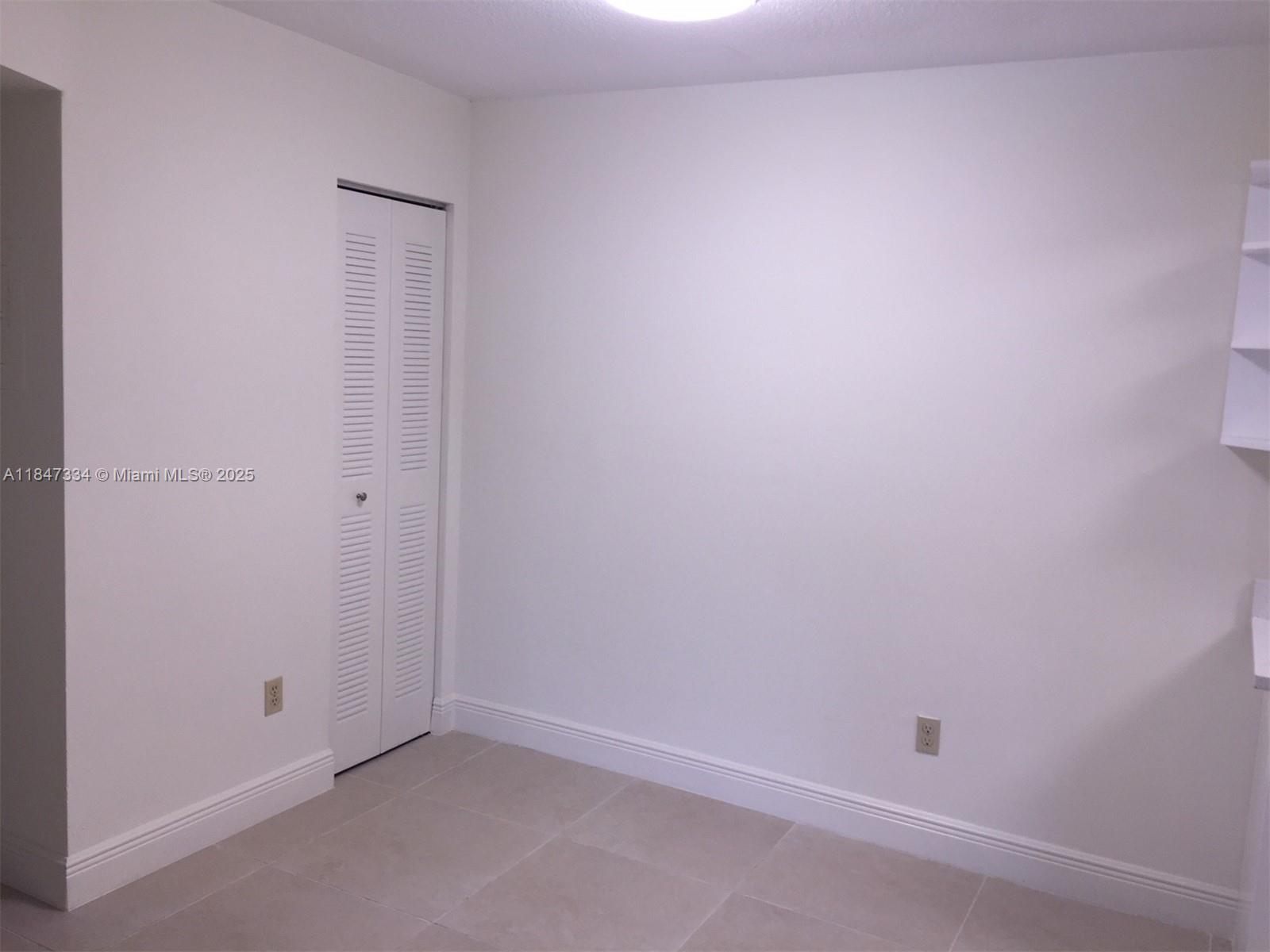 A small room features white walls, light-colored tile flooring, and a white louvered closet door — 10740 N KENDALL DR # 14, Miami FL 33176, MIAMI, FL
